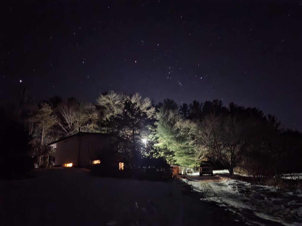 The constellation Orion hanging low over the trees and a snow-covered driveway at Otter Creek.