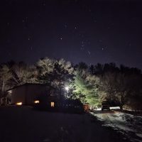 The constellation Orion hanging low over the trees and a snow-covered driveway at Otter Creek.
