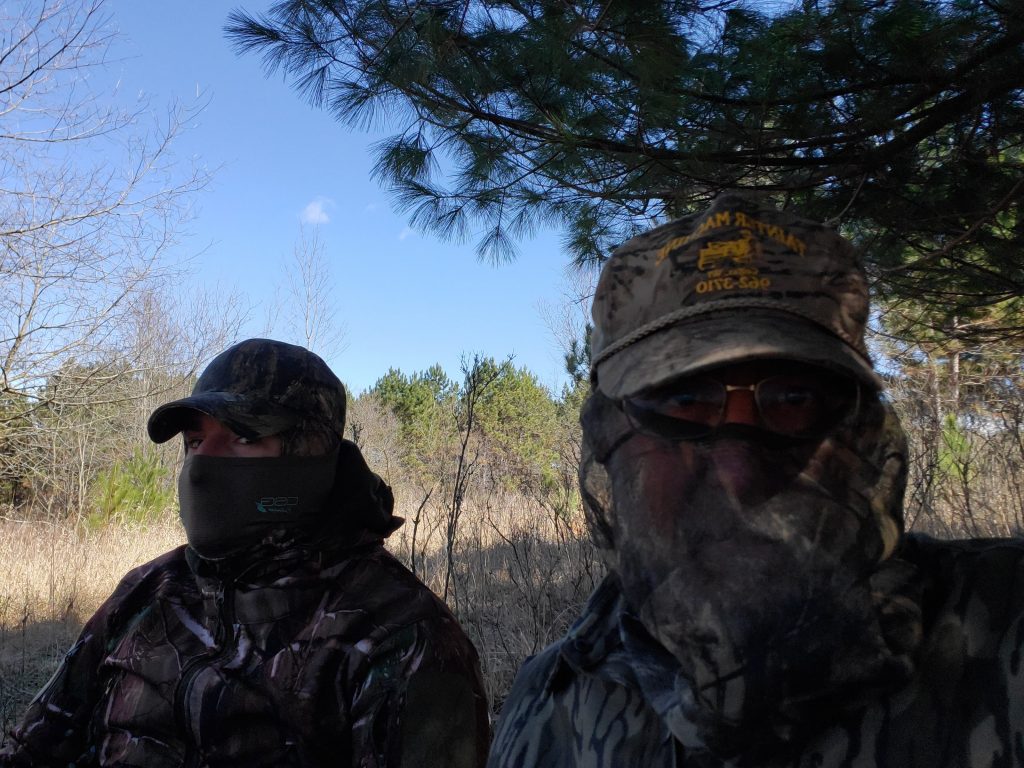 Two hunters in camouflage sitting quietly in the woods during spring turkey hunting season in Wisconsin.